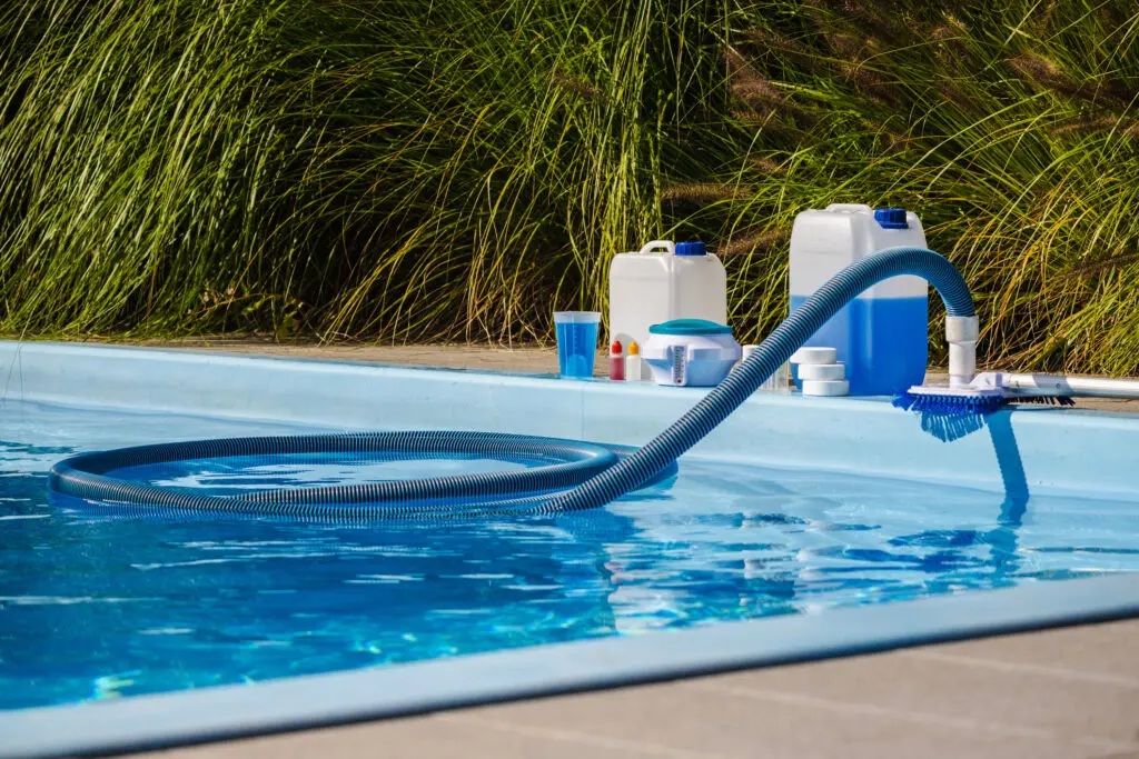 Pool cleaning equipment and supplies beside water.