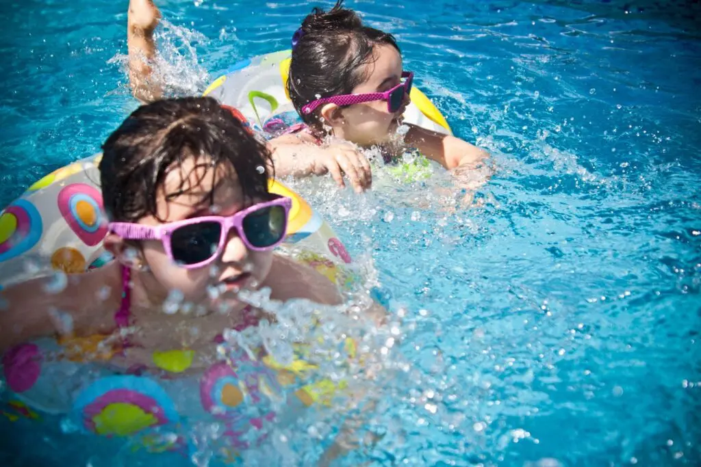 Children swimming with colorful floats and sunglasses