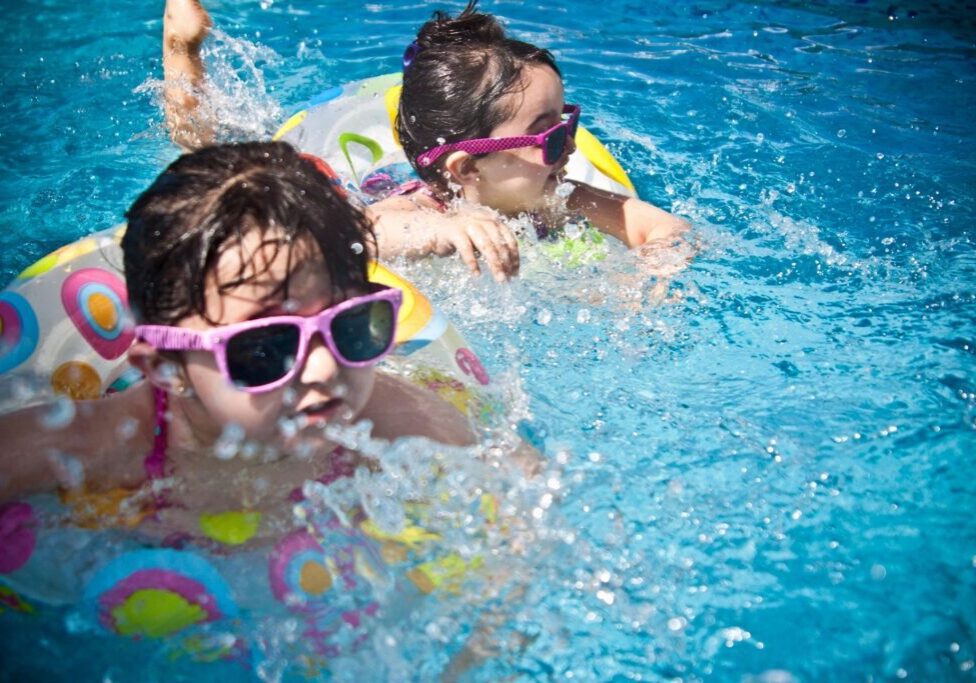 Children swimming with colorful floats and sunglasses